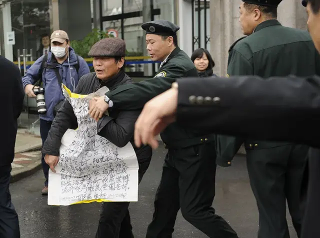 2012年2月22日,在上海浦东新区人民法院外,一名上访者(中)被一名保全人员推开。中国国家副主席习近平在最近一次访美期间表示,中国将采取实际措施改善人权状况,但他同时承认“人权状况总有改进的空间”。
