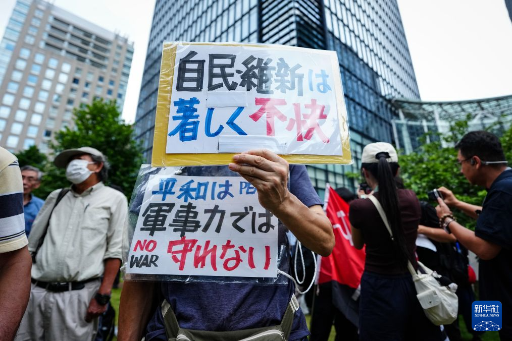 8月15日，在日本东京的淡路公园内，日本民众手持标语参加集会。新华社记者 贾浩成 摄