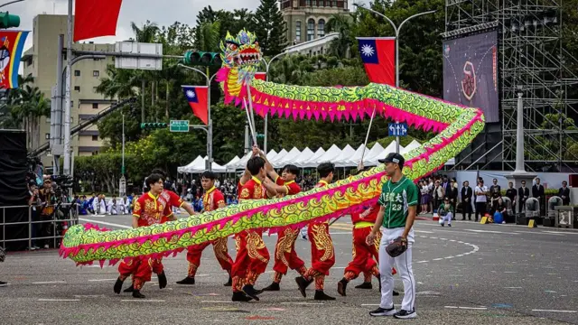 2026年10月10日台北国庆大会及庆祝活动期间,一支传统舞龙队伍舞动绿色巨龙,身旁有一名棒球选手同行。