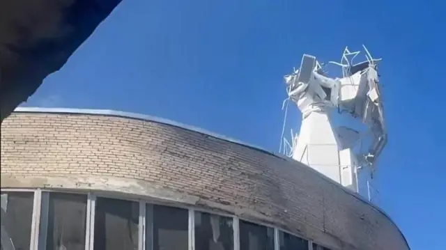 Повреждения на объекте в Белоомуте: поврежденная белая башня с антеннами и выбитые окна