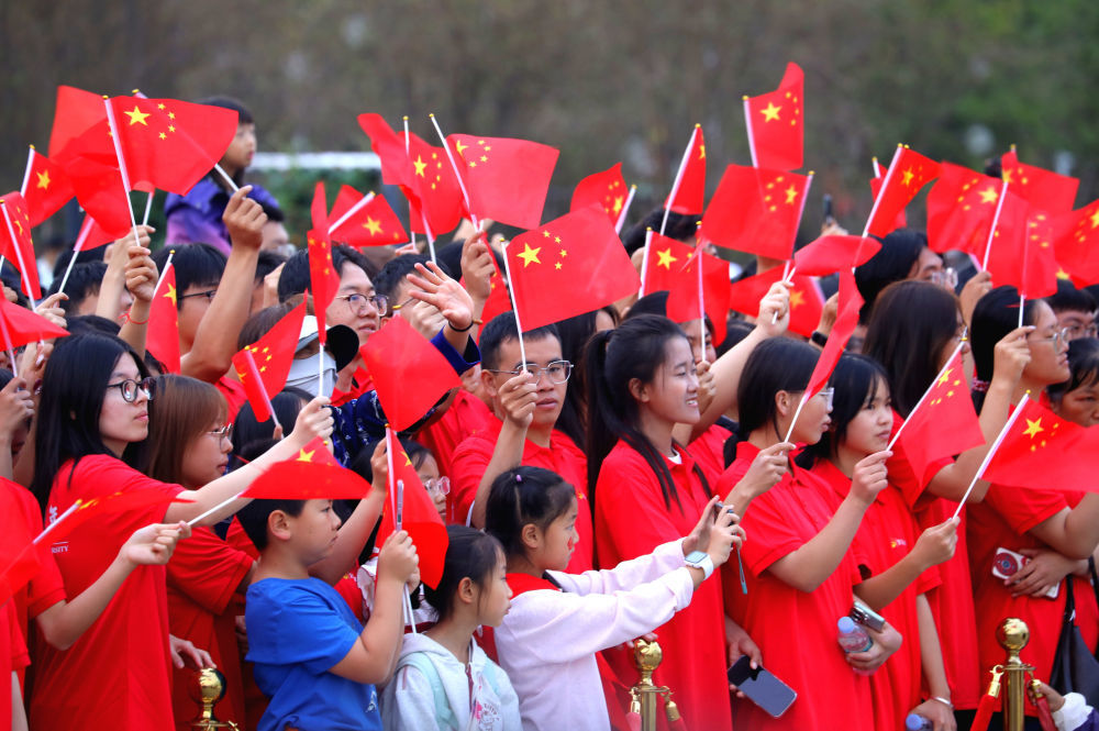 10月1日,人们在云南省昆明市东风广场参加升旗仪式后观看演出。 新华社发(郑益 摄)
