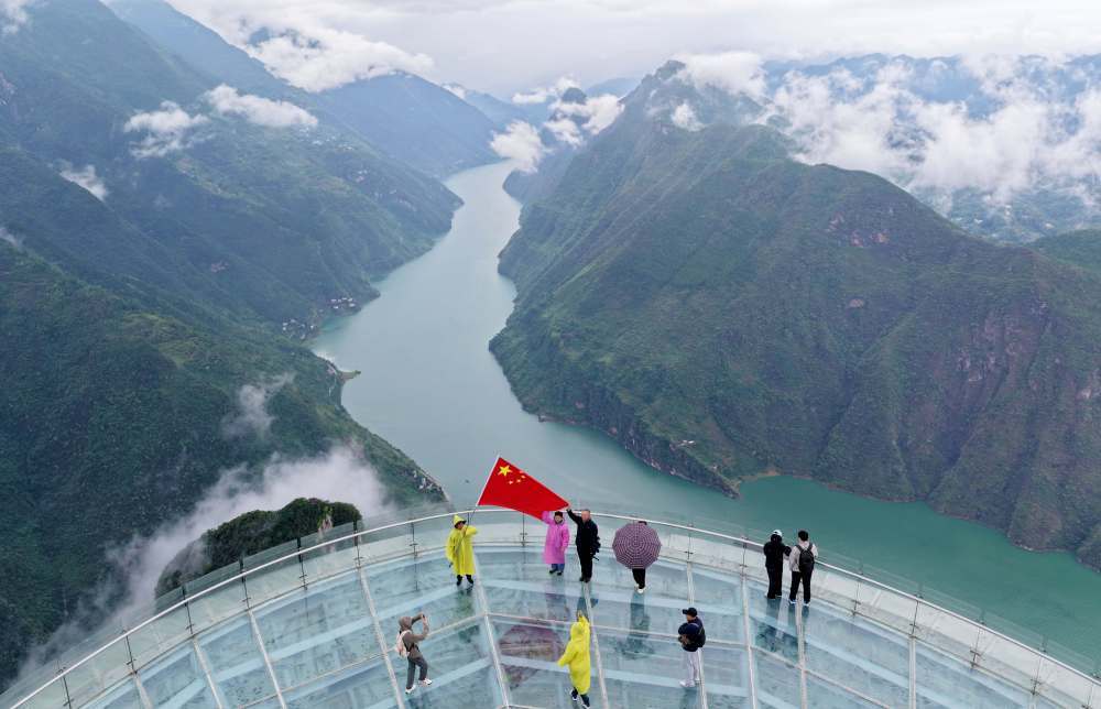 10月1日,在湖北省恩施土家族苗族自治州巴东县巫峡口景区,游客在玻璃观景平台上合影留念。新华社发(焦国斌 摄)