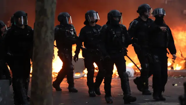 巴黎防暴警察在示威日与抗议者爆发冲突期间,走过一道燃烧中的路障(17/10/2026)