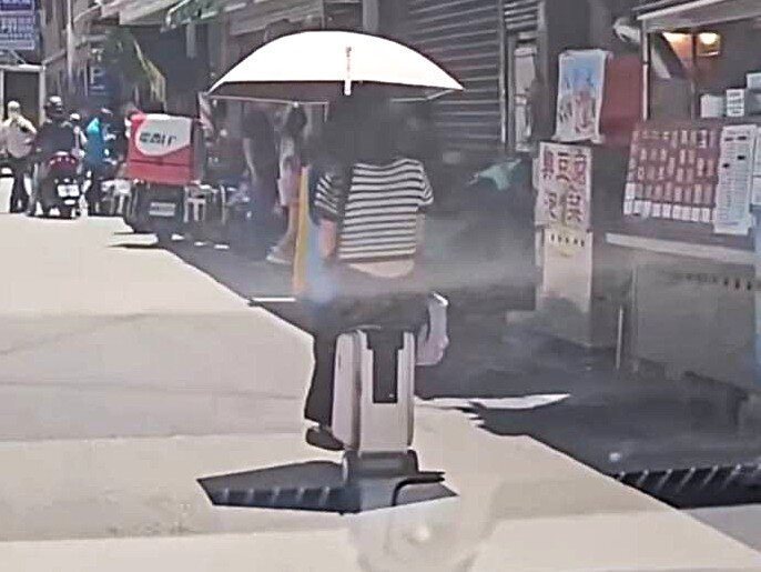 宜蘭羅東博愛醫院附近出現一名女子單手撐傘,騎著「電動行李箱」逛大街,模模很悠哉。由於這類個人行動器禁止騎上馬路,警方將通知女子到案說明並開罰。圖/翻攝自threads