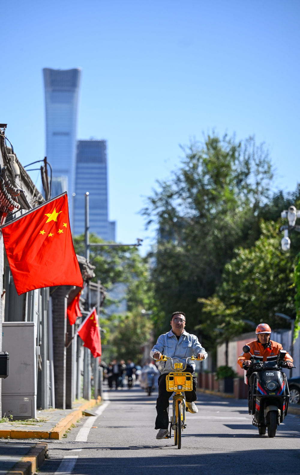 10月1日,行人骑车经过悬挂着国旗的北京东城区西总布胡同。新华社记者 陈晔华 摄