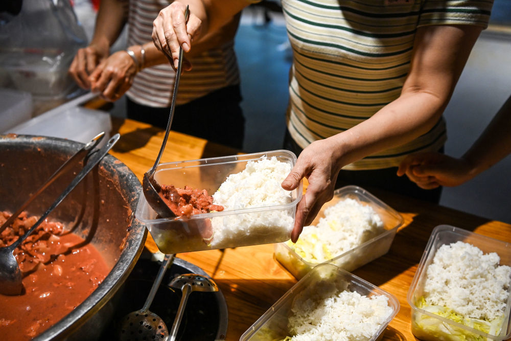 7月10日,在广西贵港市,后勤保障人员为一线救援人员准备餐食。新华社记者 曹祎铭 摄