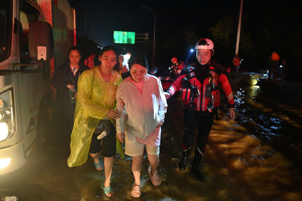 ↑ 7月7日，救援人员在广西贵港市西江教育园区连夜冒雨转移群众。