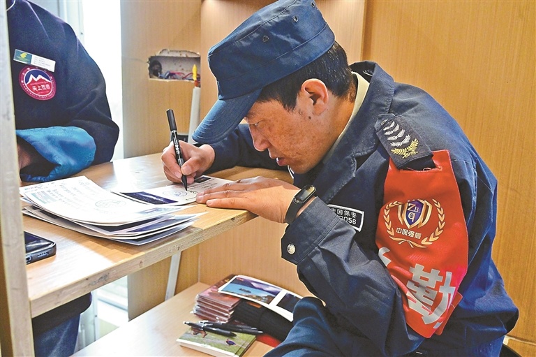 图为保安旦增久美正在为游客写藏语祝福。记者 明吉 摄