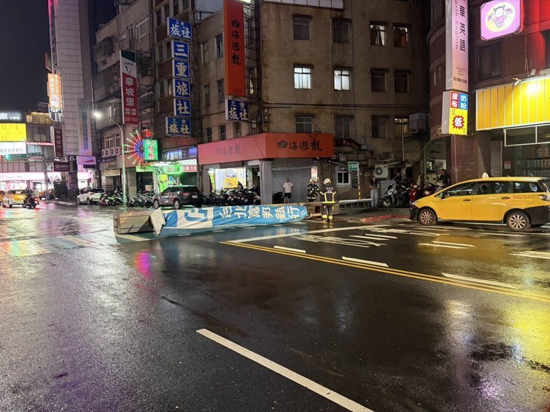 巴威颱風逼近，新北入夜後風雨增強，三重區正義北路上富邦銀行招牌突然倒下，橫在馬路上，險些擊中路過的公車、機車騎士，驚險萬分。圖／三重警分局提供