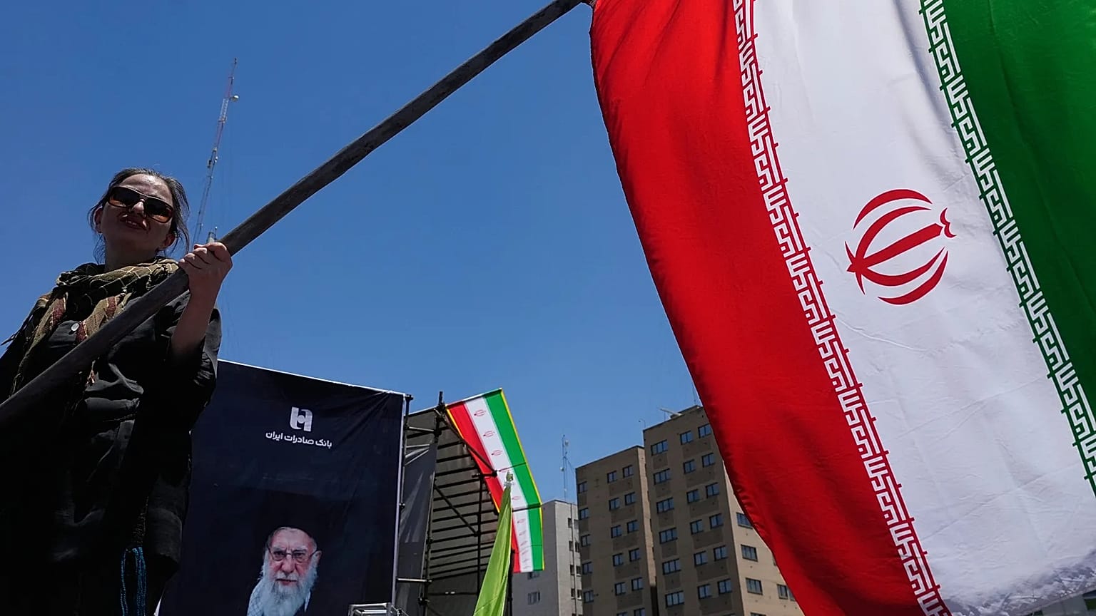Женщина размахивает флагом Ирана во время проправительственной кампании в центре Тегерана, 15 июня 2026 года.