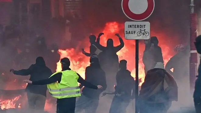 Протестующие на фоне огня в Париже