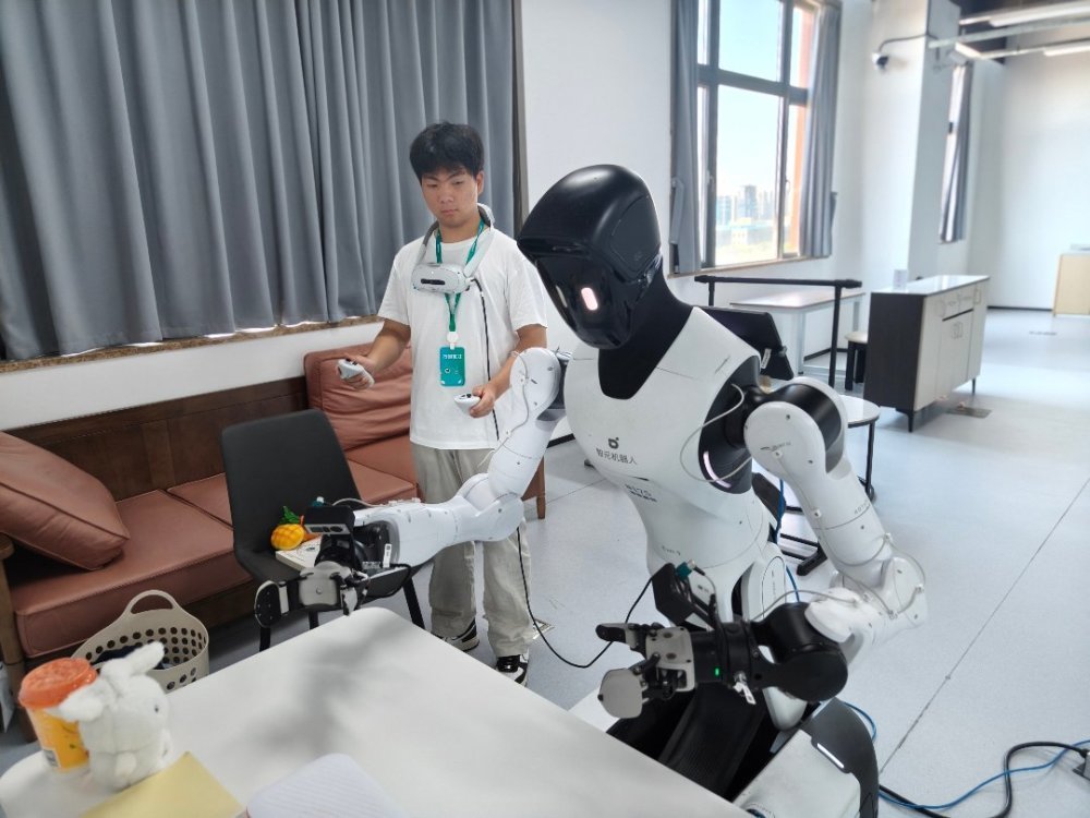 7月30日，浙江清华柔性电子技术研究院具身智能实训场里，来自郑州信息科技职业学院的学生朱思凯作为实习生，正在训练机器人抓取桌上的物件。第一次做数据采集员，他觉得很新奇，也希望未来有一天人机协同能有更大的突破。中青报·中青网记者 宁迪/摄