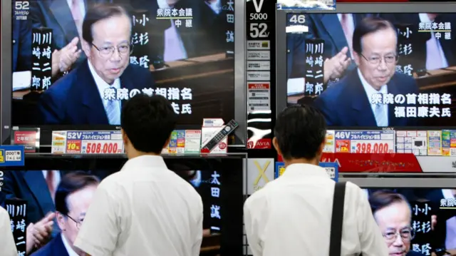 日本东京街头民众驻足收看电器店所展示的电视机正在直播的国会众议院会议情况，议会宣布福田康夫当选首相（25/9/2007）