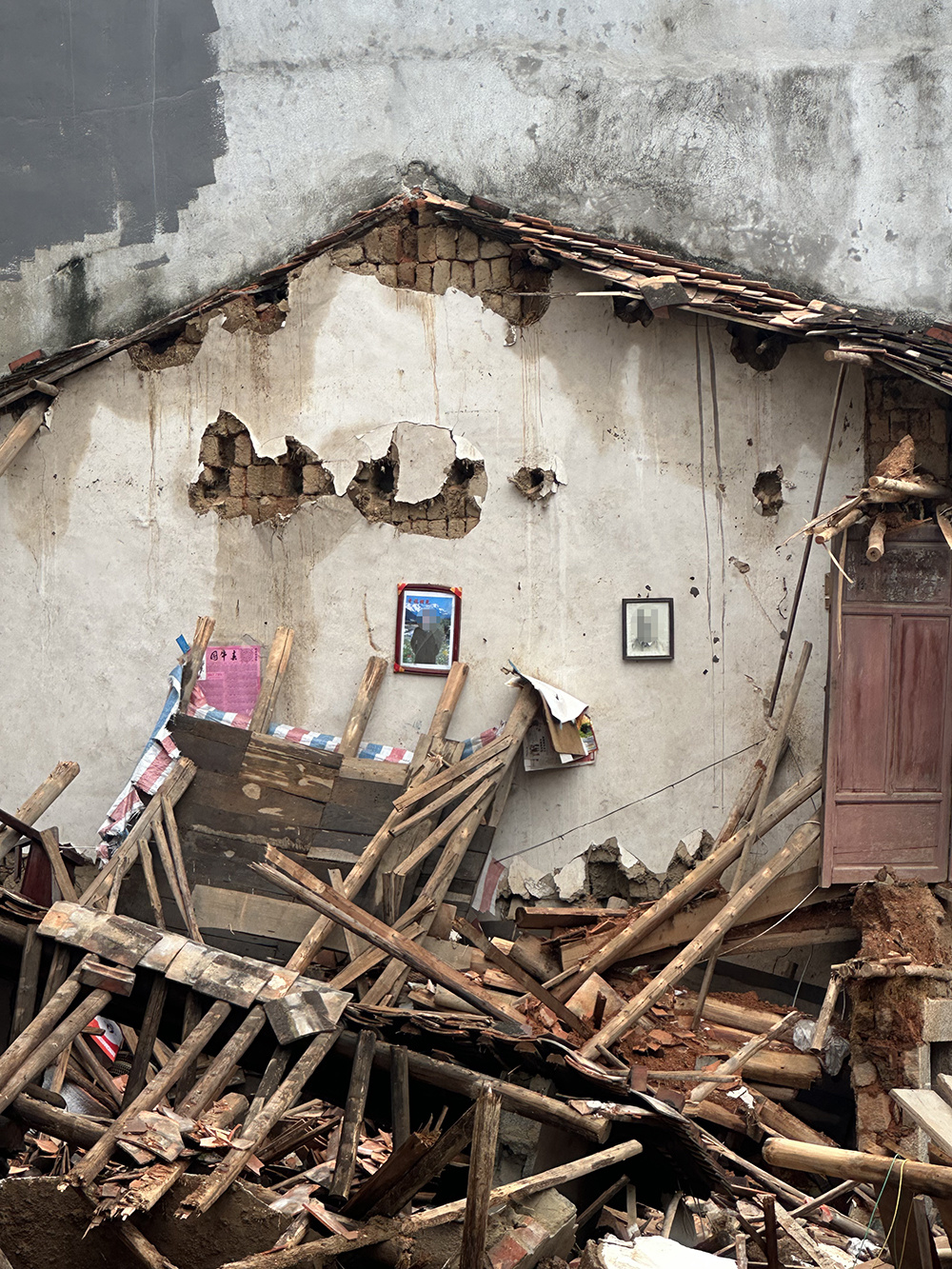 建筑体倒塌后,两幅装裱完好的人像依然端端正正地挂着。