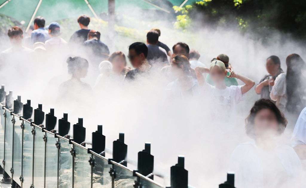 8月4日，韩国京畿道光明市佳鹤洞，持续高温天气下，前往光明溶洞的市民在洞前设置的降温水雾装置前享受水雾降温。视觉中国 图