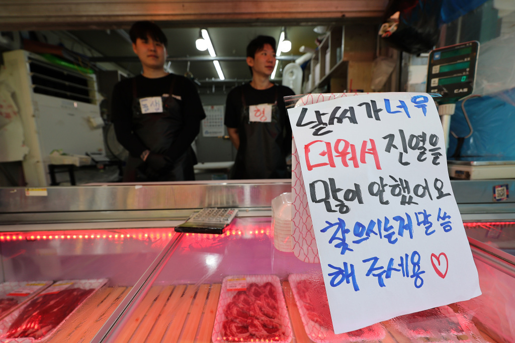 8月4日，韩国首尔，持续高温天气下，一家肉店贴出因天气炎热减少陈列的告示。视觉中国 图