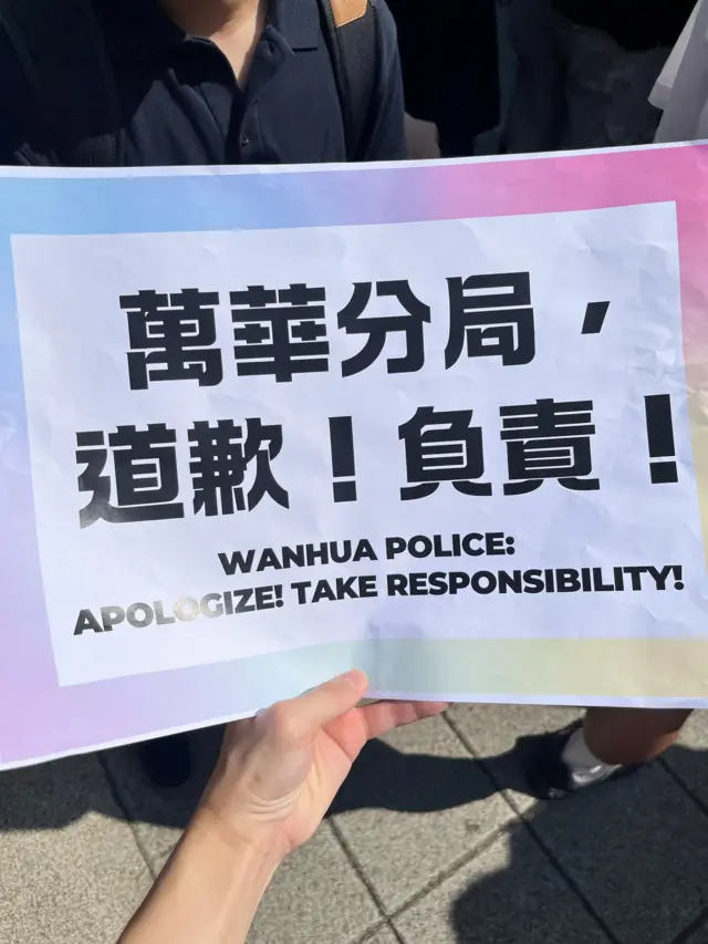 台北西门町 LGBT 社群抗议现场,一位示威者手持“万华分局,道歉!负责!”中英文标语牌(4/10/2026)