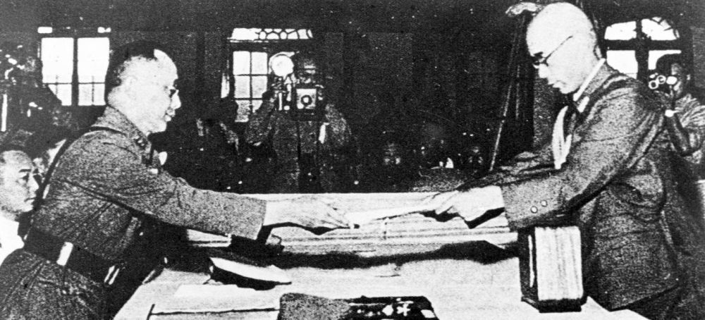 1945年9月9日,何应钦(左)在南京代表中国政府接受侵华日军总参谋长小林浅三郎递交的侵华日军总司令冈村宁次签署的投降书。新华社发