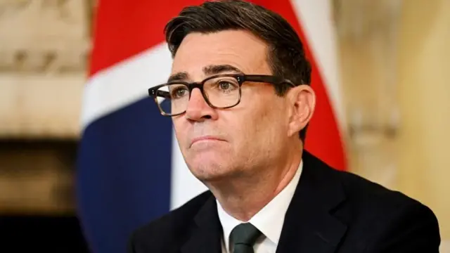 安迪·伯纳姆在唐宁街10号首相府内，坐在一面英国国旗前