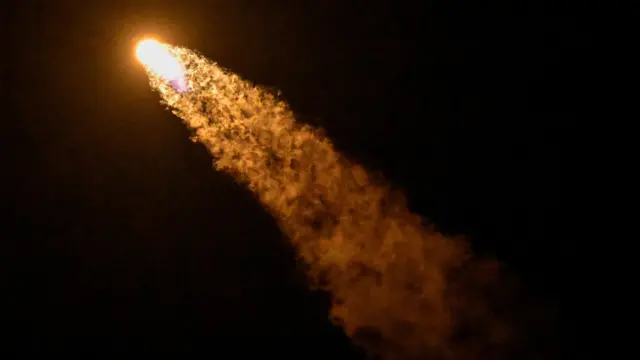 一枚发出耀眼光芒的火箭在漆黑的夜空中疾驰而去,身后拖着一缕青烟。