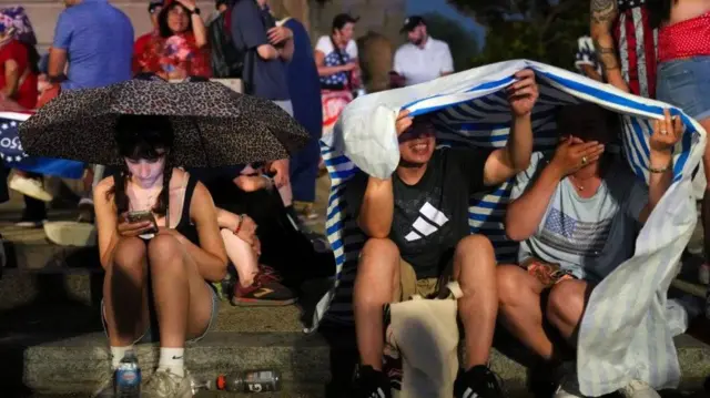 民众在暴风雨来袭的天气中躲避雨水，场景发生在华盛顿特区，当时正值美国总统唐纳德·特朗普出席的一场独立日庆祝活动集会，以纪念美国独立250周年，时间为2026年7月4日。
