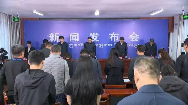 西藏吉隆镇新闻发布会现场官员与记者默哀悼念泥石流灾难死难者(中国中央电视台画面截屏30/8/2026)