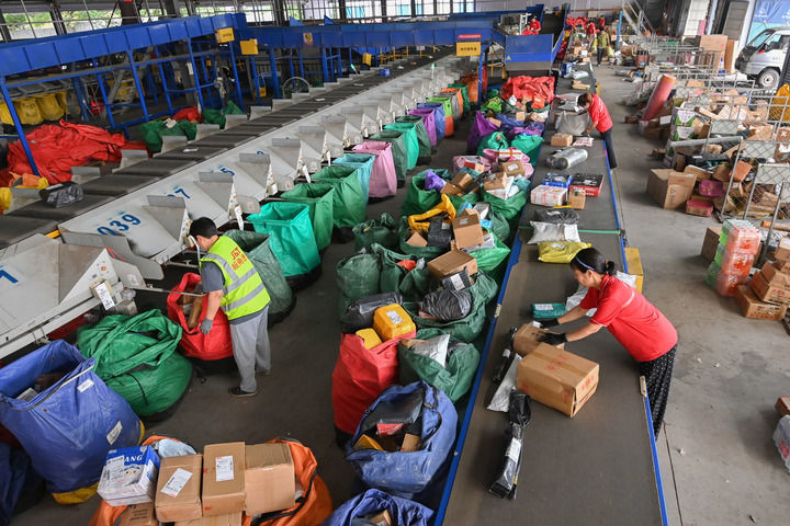 6月18日,在山东省青州市物流园区一家快递企业,工作人员在智能快递分拣流水线上忙碌。新华社发(王继林摄)