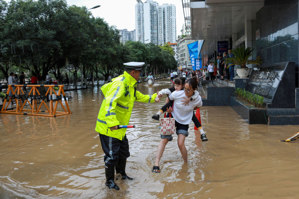 2026年5月19日，在贵州省都匀市一处积水的街道，交警帮助群众安全通行。5月18日6时至19日6时，贵州省都匀市遭遇特大暴雨。新华社发（肖伟 摄）