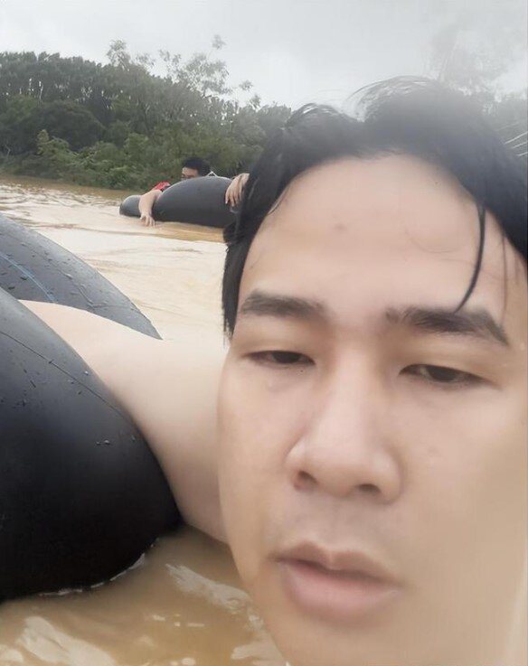 男子抱著輪胎游進村裡尋找父母。(取材自南國早報)