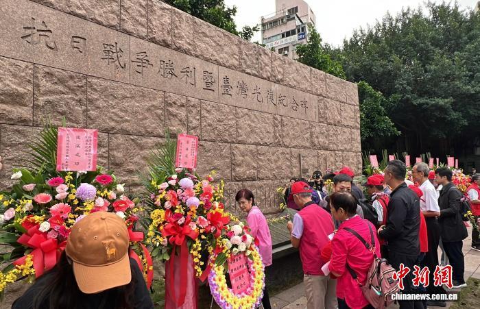 10月25日,台湾多个民间团体在台北中山堂前广场举行纪念台湾光复81周年活动。图为民众向广场上的抗日战争胜利暨台湾光复纪念碑献花。 中新社记者 路梅 摄