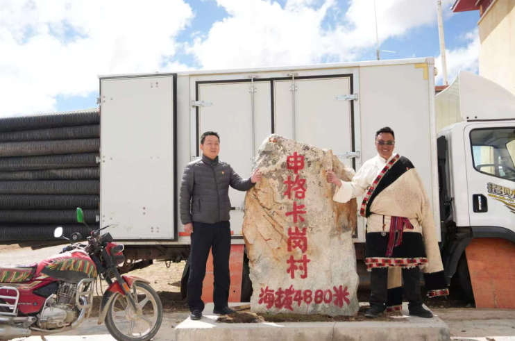 陈春友和塔规在村口4880石碑前合影。记者 琅珍 摄