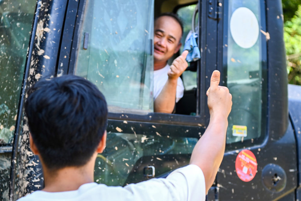 7月13日,在广西横州市,镇龙乡那旭村村民(前)给前来支援的救援人员竖起大拇指。新华社记者 曹祎铭 摄