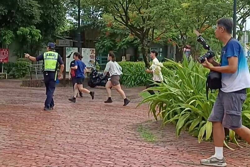 防空警報響起時，還有人在戶外奔跑，警員引導進室內避難。記者戴永華／攝影