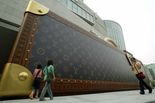 行人走过举行 LV 皮箱