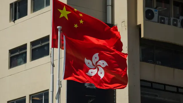 一栋楼宇外悬挂的中国国旗与香港特区区旗,香港旗帜位置比中国国旗为低(24/7/2026)