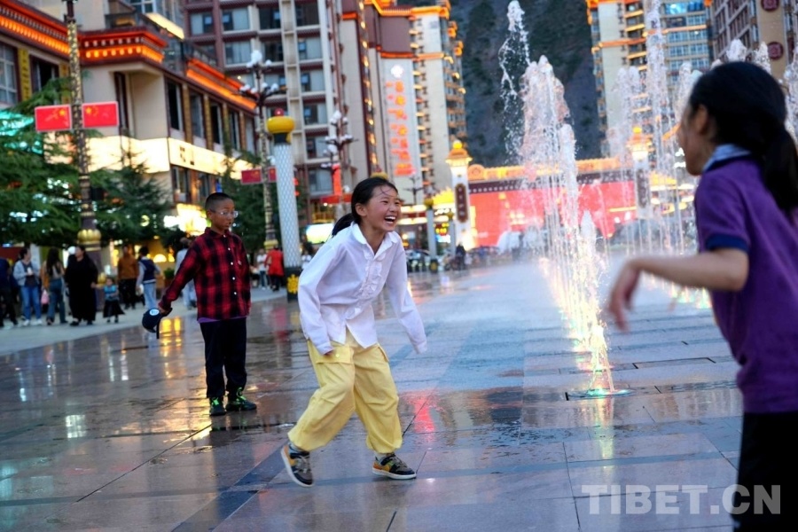 傍晚的茶马广场，孩子们围着喷泉奔跑嬉闹