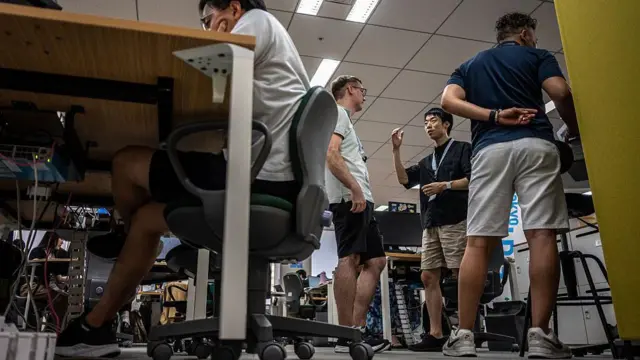 东京都厅内一群作随意短袖衣裤打扮的公务员在交谈（14/7/2026）