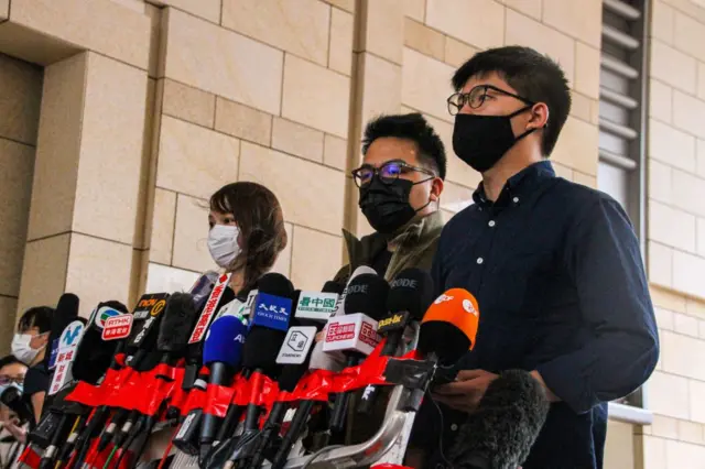 2020年11月23日，香港社运人士周庭、林朗彦和黄之锋进入西九龙法院，就非法集结罪名认罪。他们在出庭前会见记者。