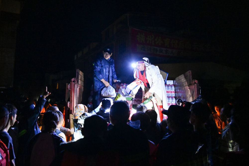 7月6日，在广西南宁横州市校椅镇六蓝村，救援人员在分发物资。新华社记者 曹祎铭 摄