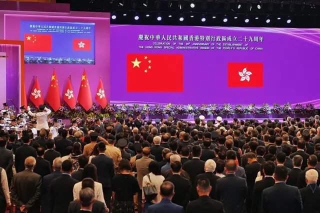 2026年7月1日,在香港湾仔的香港会议展览中心,现场举办庆祝香港成立29周年活动。多人站着背向镜头,眼望前方的中国国旗及特区区旗。
