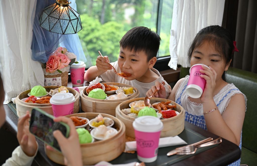 7月5日，游客在“老爸茶·海口巴士”上品尝茶点。新华社记者 郭程 摄