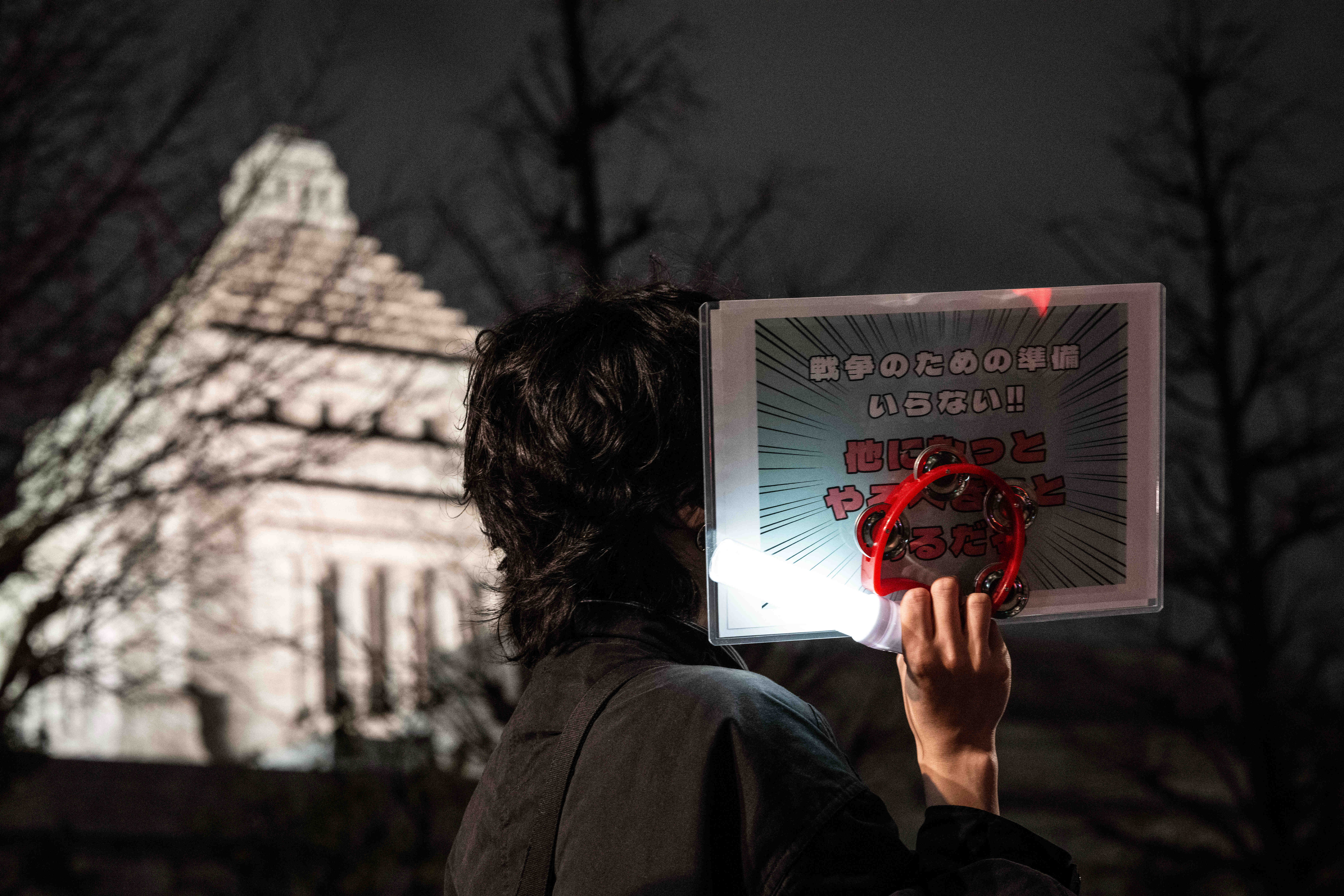 2月24日,在日本东京的众议院第二议员会馆前,民众手持标语参加抗议活动。新华社记者贾浩成摄